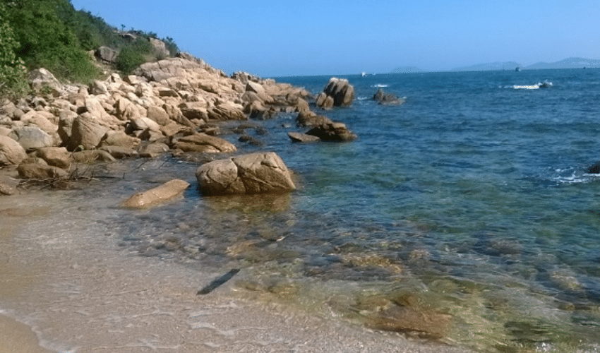 View of Bai Rang Beach in Da Nang with clear blue sea and rocky shoreline