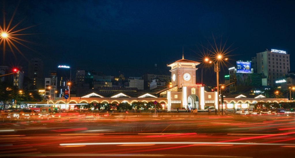 A colorful photo of Ben Thanh Market entrance with local vendors and tourists walking around