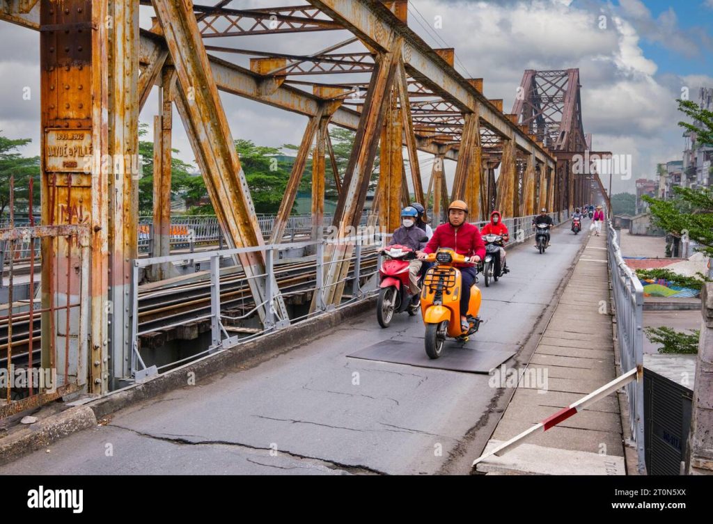 Motorbikes crossing Long Bien Bridge with Hanoi skyline in the background