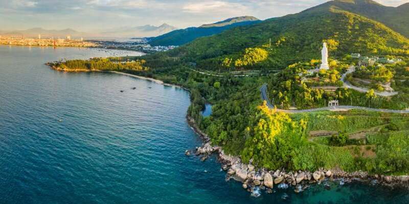 A panoramic view of Son Tra Nature Reserve with green forest, winding roads, and the blue sea in Da Nang, Vietnam