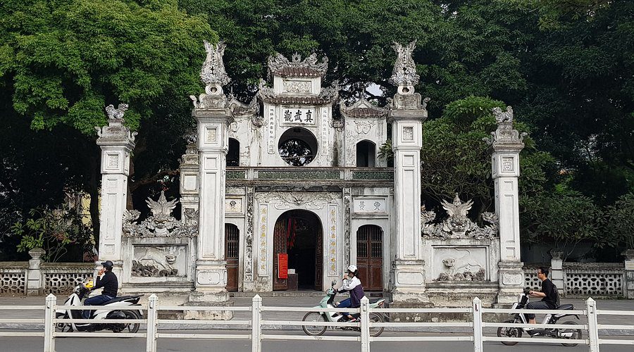 Main gate of Quan Thanh Temple with traditional tiled roof and stone statues in Hanoi