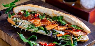Banh mi sandwich filled with pork, pickled vegetables, and herbs in Saigon street food stall