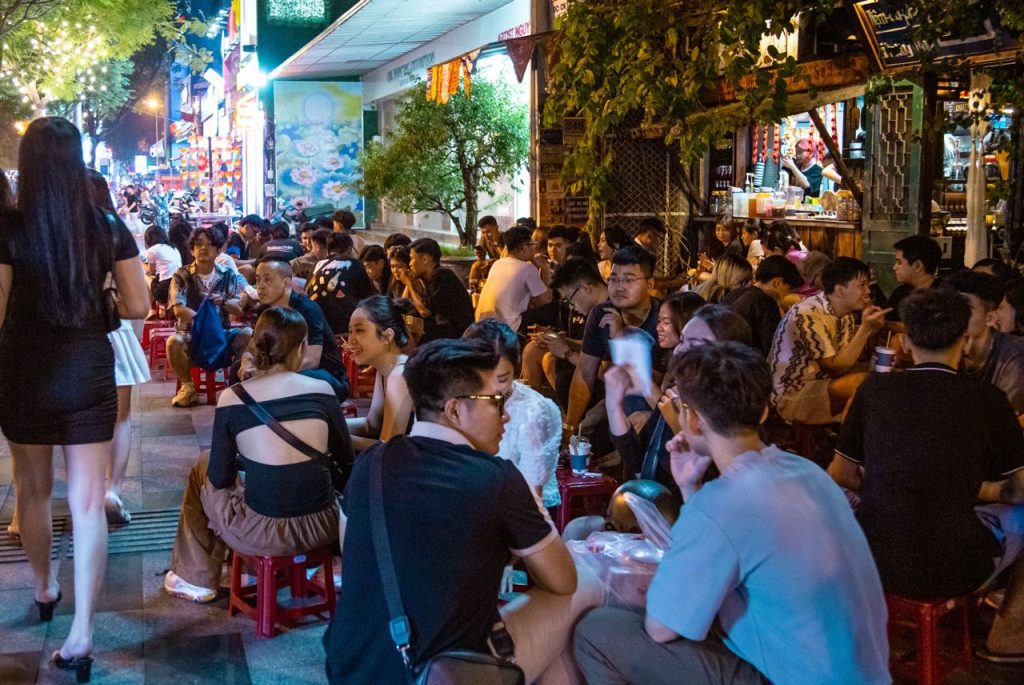 People enjoying sidewalk coffee in Saigon with small stools and street view