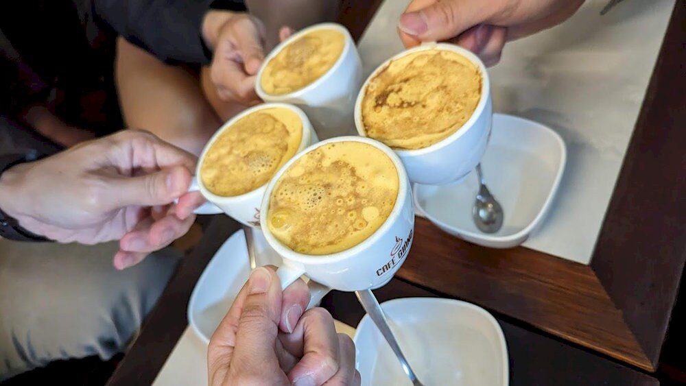 A cup of Hanoi egg coffee with creamy foam in a traditional cup