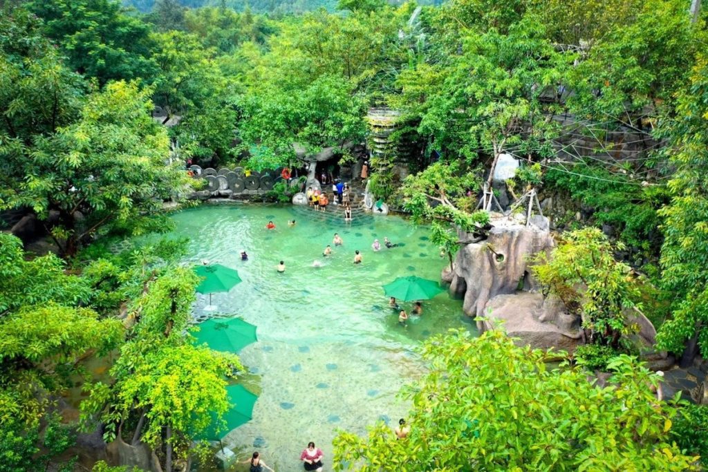 Visitors enjoying hot spring pools surrounded by lush nature at Nui Than Tai, Da Nang