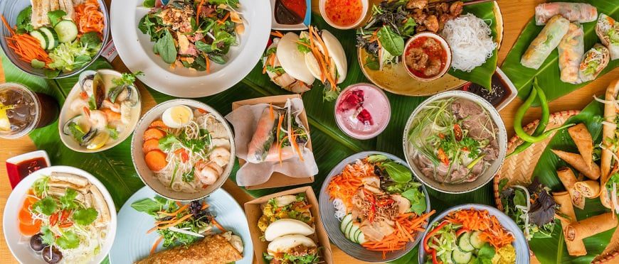 Traditional Saigon food with banh xeo, pho, and broken rice on a wooden table