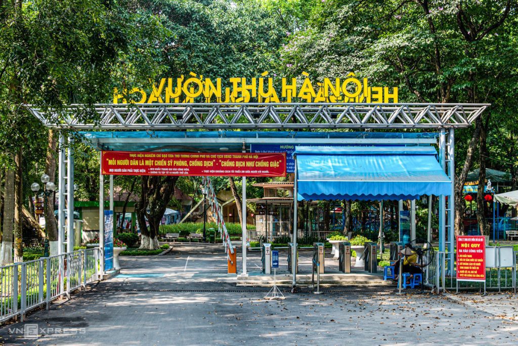 A peaceful view of Thu Le Park and Hanoi Zoo with green trees and families enjoying the day