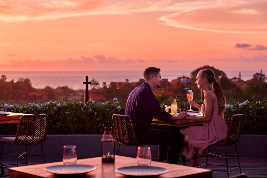 Couple enjoying coffee at a romantic rooftop cafe at sunset